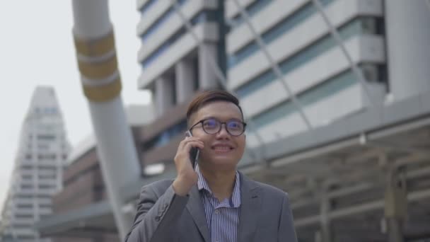 都会を歩く友人と電話をかけるハンサムなアジアのビジネスマンの肖像画 スローモーション撮影 — ストック動画