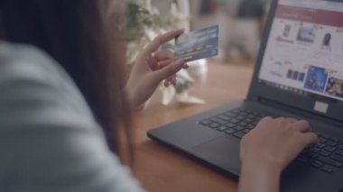 Evde bir kredi kartı ile dizüstü bilgisayar alışveriş online kullanarak ellerini genç Asyalı kadın kapatın. 