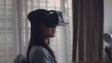 Slow Motion: Çekici portre güzel genç Asyalı kadın bir oyun oynarken ve Vr gözlük film izlerken. Mutlu Asyalı kız evde 3d sanal gerçeklik kulaklık kullanarak.