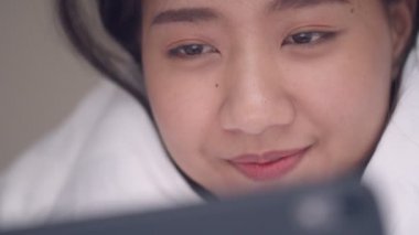 Online sosyal medya paylaşım yaşam tarzı tarama bir tablet kullanarak yatak odasında portre genç Asyalı kadın kapatın.
