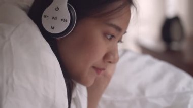 Portre Asyalı kadın müzik dinleme ve yatak odasında online sosyal medya paylaşım yaşam tarzı tarama bir tablet kullanarak.