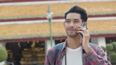 Çekici yalnız turistler Tayland tapınağında arkadaşlarıyla gezip sohbet eden Asyalı bir adam. Asyalı blogcu mutlu mesut seyahat ediyor..