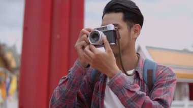 Yakışıklı Asyalı genç turistlerin gülümseyen portresi Tayland 'ın dev salıncağının fotoğrafını çekiyor. Asyalı blogcu mutlu mesut seyahat ediyor..