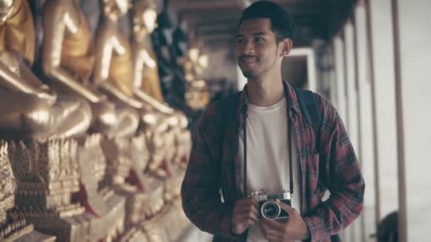 魅力的な若いアジア人男性のソロ観光客が寺院内を歩き回り 寺院タイで写真を撮る アジアの男性ブロガー幸せなレジャーライフスタイル旅行を楽しむ — ストック動画