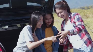 Genç Asyalı bir kadın grubu, arkadaşlarıyla birlikte yaz tatili için doğada kamp yaparken cep telefonundan fotoğraf çektiriyorlar..