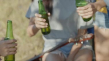 Genç Asyalı bir gencin el ele tutuşması. Bira ve kadeh tokuşturma..