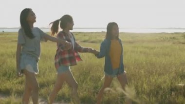 Çekici üç genç insan, güneş batarken koşan Asyalı kadınlar yaz tatilinde birlikte eğleniyorlar. Yaşam tarzı tatil tatili. Bir dağ geçmişine sahip olmak.