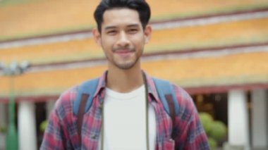 Tayland tapınağında gezen ve fotoğraf çeken yakışıklı Asyalı genç adamın gülümseyen portresi. Asyalı blogcu mutlu mesut seyahat ediyor..