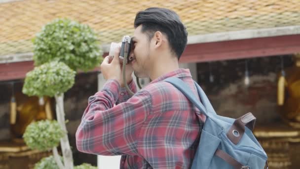 ハンサムな若いアジアの男の観光客の笑顔の旅行や寺院タイで写真を撮る アジアの男性ブロガー幸せなレジャーライフスタイル旅行を楽しむ — ストック動画