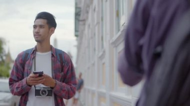 Gülümse yakışıklı turist akıllı telefon kullanarak Tayland 'da caddenin kenarında dururken haritayı kontrol ediyor. Genç Asyalı blogcu. Keyifli bir hayat tarzı seyahatinin keyfini çıkarıyor..