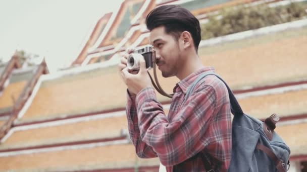 魅力的な若いアジアの男性観光客の旅行や寺院タイで写真を撮るフィルムカメラを使用して歩く アジアの男性ブロガー幸せなレジャーライフスタイル旅行を楽しむ — ストック動画