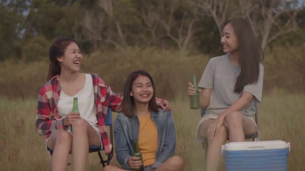一群年轻的亚洲少女坐在椅子上 和朋友们一起在大自然露营 一边喝啤酒 一边碰杯 和朋友一起喝啤酒 边看日落 — 图库视频影像