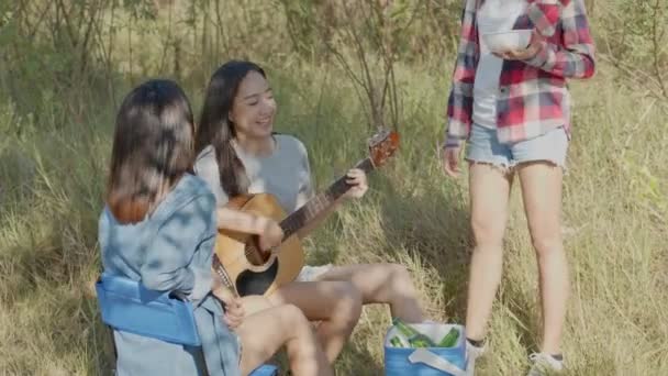 一群年轻的亚洲女子 与在大自然露营的朋友们在一起玩吉他 喝啤酒 她们很开心 — 图库视频影像