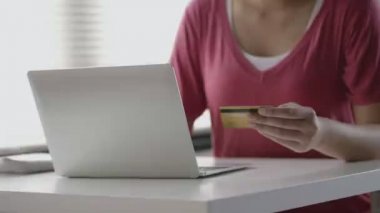 Ofiste otururken bilgisayardan alışveriş yaparak kredi kartı ödemesini yapan Asyalı kadını kapat..