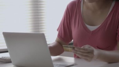 İnternetten bilgisayar alışverişi yapan güzel bir Asyalı kadının gülümseyen portresini kapat ve ofis odasında otururken kredi kartı ödemesini kullan..