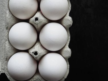 Siyah arka plan üzerinde bir kutu içinde beyaz yumurta