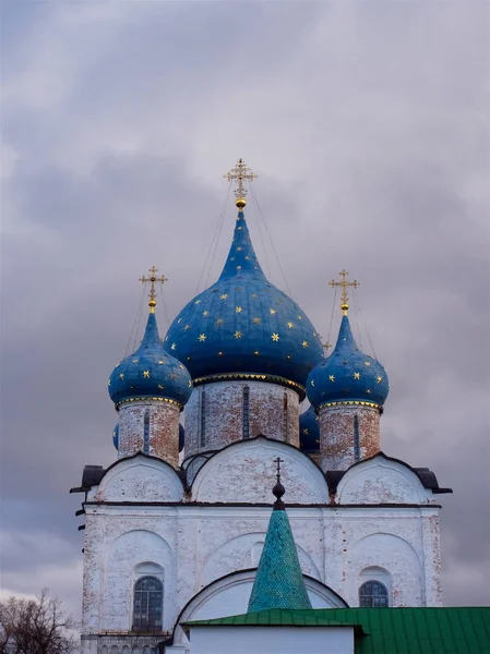 the blue with gold stars domes of the Orthodox Church on the bakground of stormy purple sky, Suzdal Kremlin Russia