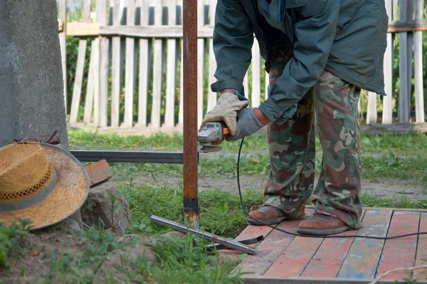 a man working with angle grinder in the backyard in the summer on a sunny day