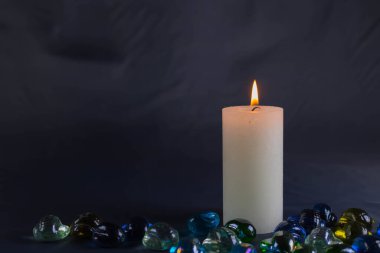 Arkaplanı yanan küçük bir alevi olan ince bir mum. Mumlar eski bir masada. Güzel koyu arkaplan. Dini kavram.