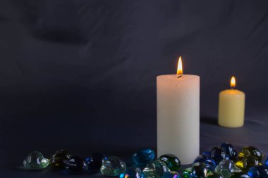 Arkaplanı yanan küçük bir alevi olan ince bir mum. Mumlar eski bir masada. Güzel koyu arkaplan. Dini kavram.