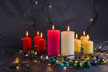 Arkaplanı yanan küçük bir alevi olan ince bir mum. Mumlar eski bir masada. Güzel koyu arkaplan. Dini kavram.