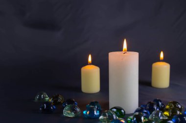 Arkaplanı yanan küçük bir alevi olan ince bir mum. Mumlar eski bir masada. Güzel koyu arkaplan. Dini kavram.