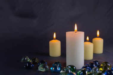 Arkaplanı yanan küçük bir alevi olan ince bir mum. Mumlar eski bir masada. Güzel koyu arkaplan. Dini kavram.