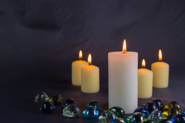 Arkaplanı yanan küçük bir alevi olan ince bir mum. Mumlar eski bir masada. Güzel koyu arkaplan. Dini kavram.