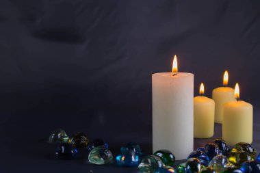 Arkaplanı yanan küçük bir alevi olan ince bir mum. Mumlar eski bir masada. Güzel koyu arkaplan. Dini kavram.