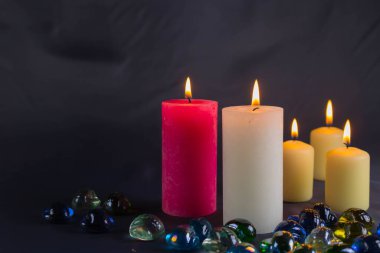 Arkaplanı yanan küçük bir alevi olan ince bir mum. Mumlar eski bir masada. Güzel koyu arkaplan. Dini kavram.