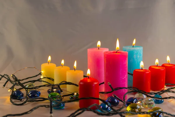 Arkaplanı yanan küçük bir alevi olan ince bir mum. Mumlar eski bir masada. Güzel koyu arkaplan. Dini kavram.