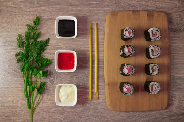 Sushi set is served on a plate, Board on the background. Traditional Japanese cuisine, sushi rolls close-up. Top view of assorted sushi rolls on white plate close-up. Fresh delicious beautiful sushi rolls on a dark background. Elements of Japanese cu