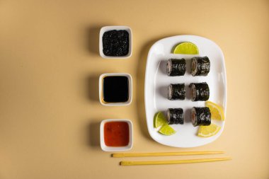 Hafif bir arka planda bir suşi rulosu servis edilir. Suşili lezzetli geleneksel Japon yemekleri..