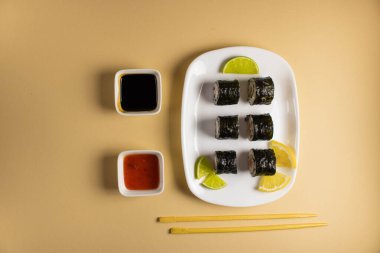 Hafif bir arka planda bir suşi rulosu servis edilir. Suşili lezzetli geleneksel Japon yemekleri..