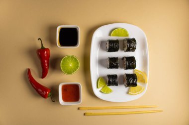 Hafif bir arka planda bir suşi rulosu servis edilir. Suşili lezzetli geleneksel Japon yemekleri..