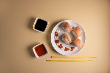 Hafif bir arka planda bir suşi rulosu servis edilir. Suşili lezzetli geleneksel Japon yemekleri..