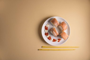 Hafif bir arka planda bir suşi rulosu servis edilir. Suşili lezzetli geleneksel Japon yemekleri..