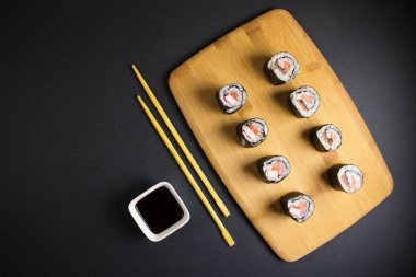 Koyu bir arka planda bir suşi rulosu servis edilir. Suşili lezzetli geleneksel Japon yemekleri..