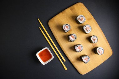 Koyu bir arka planda bir suşi rulosu servis edilir. Suşili lezzetli geleneksel Japon yemekleri..