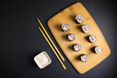 Koyu bir arka planda bir suşi rulosu servis edilir. Suşili lezzetli geleneksel Japon yemekleri..