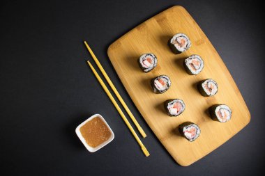 Koyu bir arka planda bir suşi rulosu servis edilir. Suşili lezzetli geleneksel Japon yemekleri..