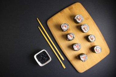 Koyu bir arka planda bir suşi rulosu servis edilir. Suşili lezzetli geleneksel Japon yemekleri..