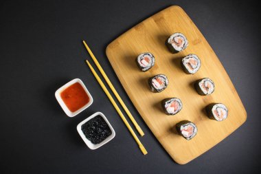 Koyu bir arka planda bir suşi rulosu servis edilir. Suşili lezzetli geleneksel Japon yemekleri..