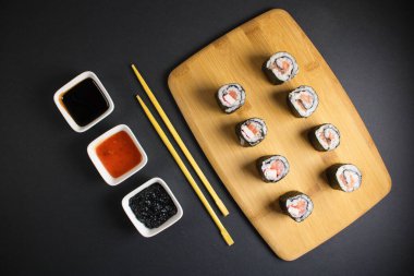 Koyu bir arka planda bir suşi rulosu servis edilir. Suşili lezzetli geleneksel Japon yemekleri..