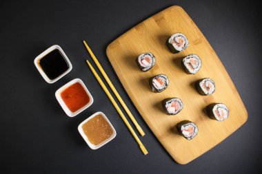 Koyu bir arka planda bir suşi rulosu servis edilir. Suşili lezzetli geleneksel Japon yemekleri..