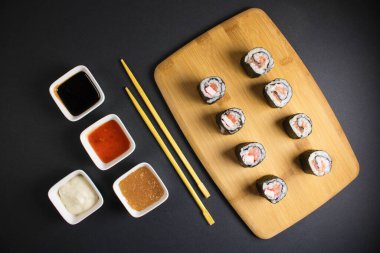 Koyu bir arka planda bir suşi rulosu servis edilir. Suşili lezzetli geleneksel Japon yemekleri..