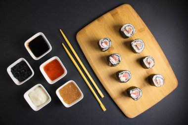 Koyu bir arka planda bir suşi rulosu servis edilir. Suşili lezzetli geleneksel Japon yemekleri..