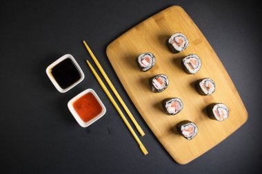 Koyu bir arka planda bir suşi rulosu servis edilir. Suşili lezzetli geleneksel Japon yemekleri..