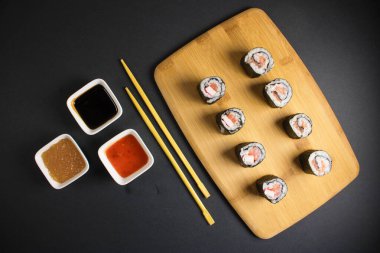 Koyu bir arka planda bir suşi rulosu servis edilir. Suşili lezzetli geleneksel Japon yemekleri..