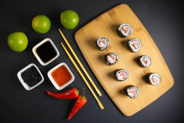 Koyu bir arka planda bir suşi rulosu servis edilir. Suşili lezzetli geleneksel Japon yemekleri..